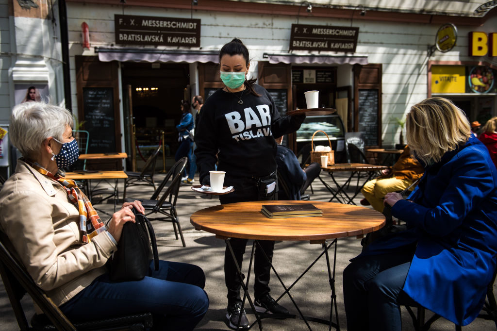 A waitress wearing a face mask serves clients at the terrace of a cafe in Bratislava on May 6, 2020, amid the novel coronavirus COVID-19 pandemic. - The Slovakian government is easing restrictions because of the low number of new coronavirus infections. Slovakia reopens from May 6, 2020 shops and most service providers, restaurants -- for outdoor seating only -- as well as museums and galleries. (Photo by VLADIMIR SIMICEK / AFP) (Photo by VLADIMIR SIMICEK/AFP via Getty Images)