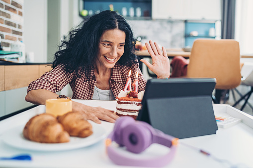 Happy woman with birthday cake having a video call
