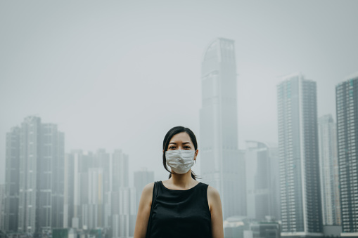 Young woman wearing protective face mask in city due to the polluted air