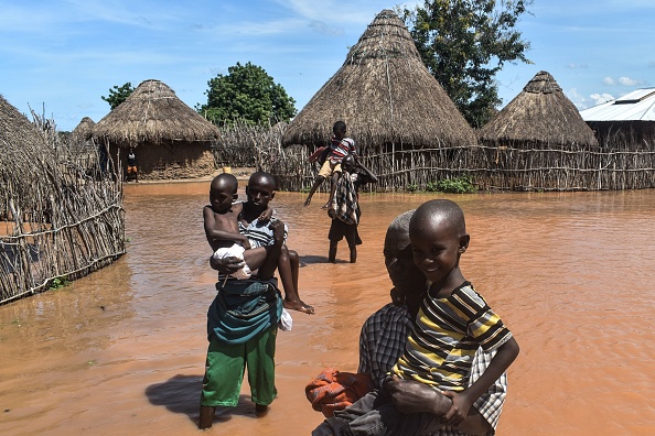 A picture taken on April 27, 2018 shows men carrying children in flooded area after the Tana River overflowed at Onkolde Village, in coastal region of Kenya. - About 64 000 people have displaced from the flooded area, according to Kenya Red Cross. (Photo by ANDREW KASUKU / AFP)        (Photo credit should read ANDREW KASUKU/AFP via Getty Images)