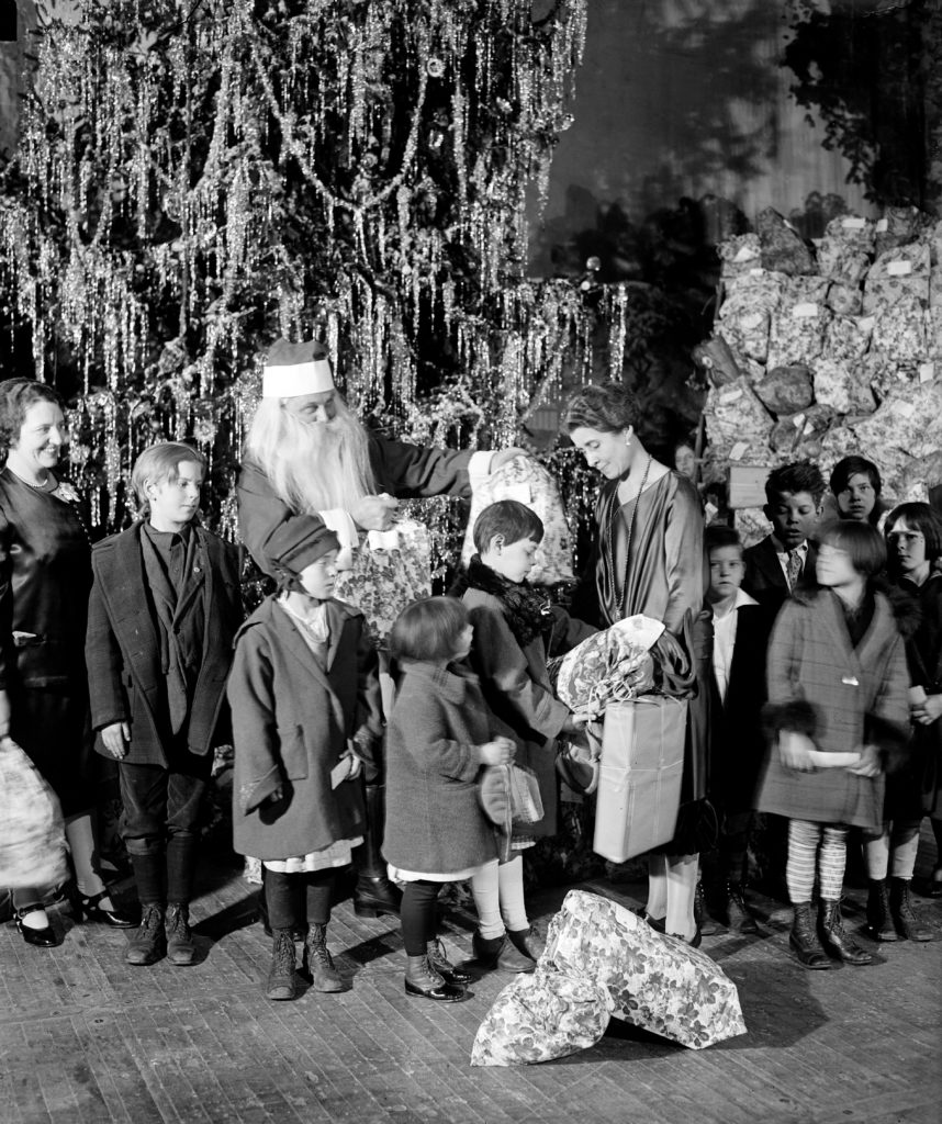 Grace Coolidge, Santa Claus, and children next to Christmas tree ca. December 1927