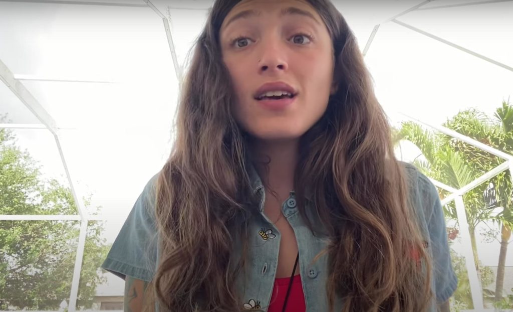 Amanda of Art Van Grow talks directly to camera wearing a blue shirt in a greenhouse