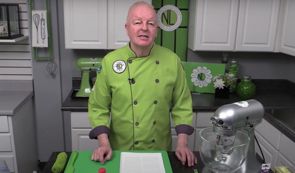 dMedium shot of chef Nicholas Lodge in his kitchen, wearing his distinctive green chef's jacket