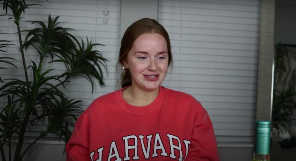 Ashlyn Vanhorn wearing a red Harvard University sweater looking down and to the side