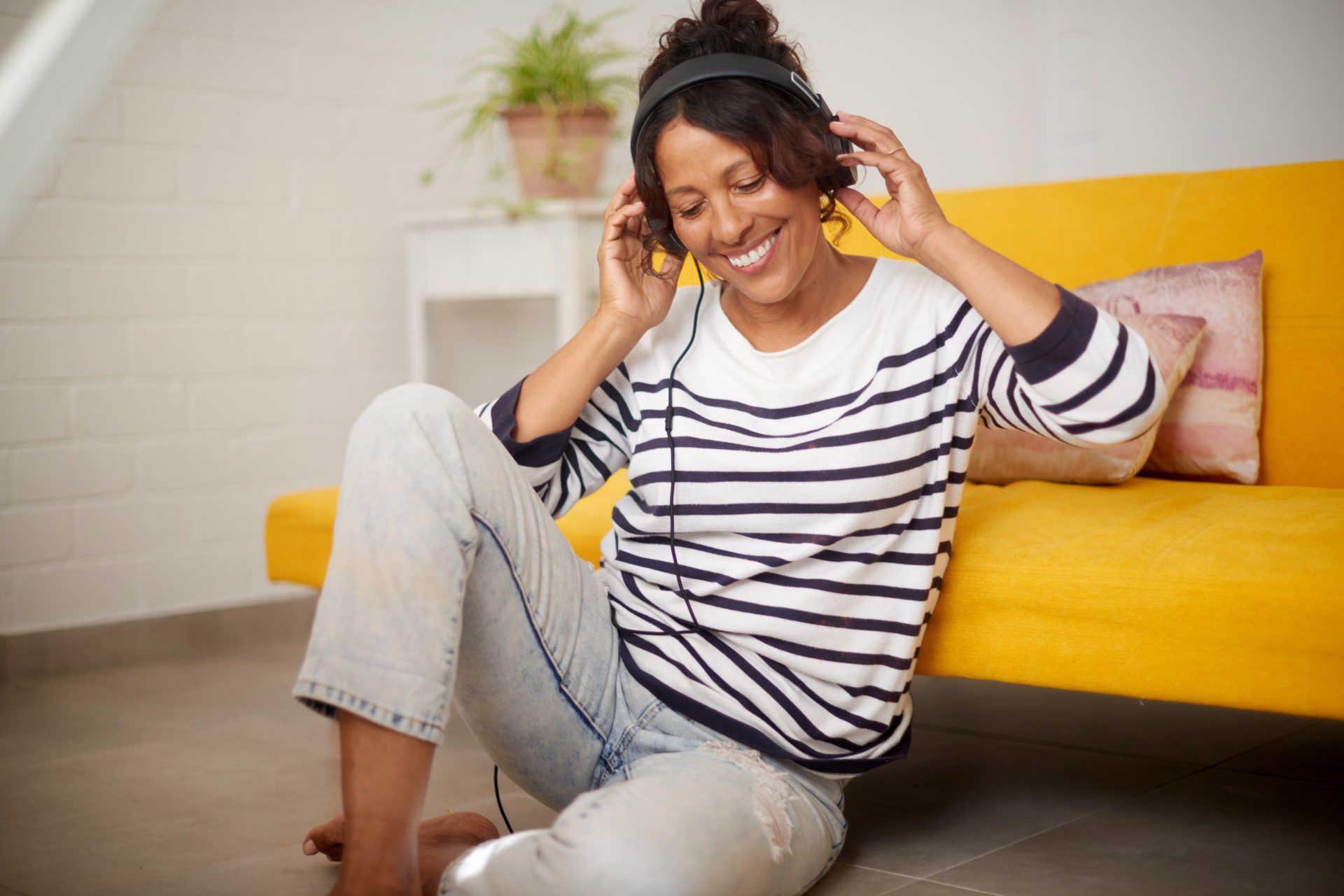 Music, relax and retirement with a senior or elderly woman listening with headphones on the floor at home. Carefree time to listen to the radio or audio while resting and relaxing in the living room