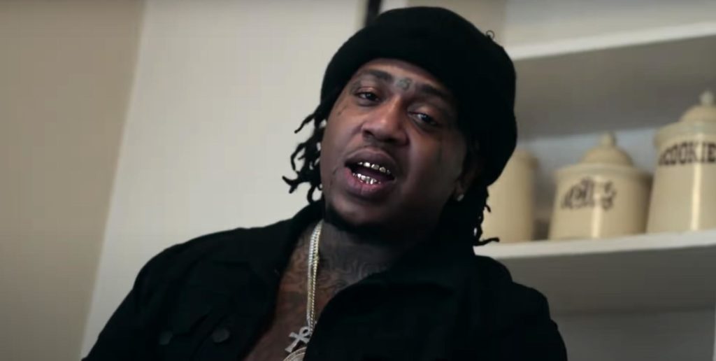 Rapper Chucky Trill wearing a black hat and gold chain