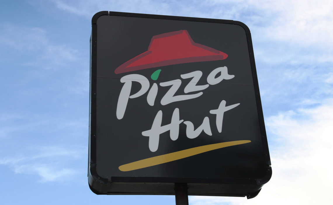Pizza Hut logo on a vertical stand with a blue sky in the background