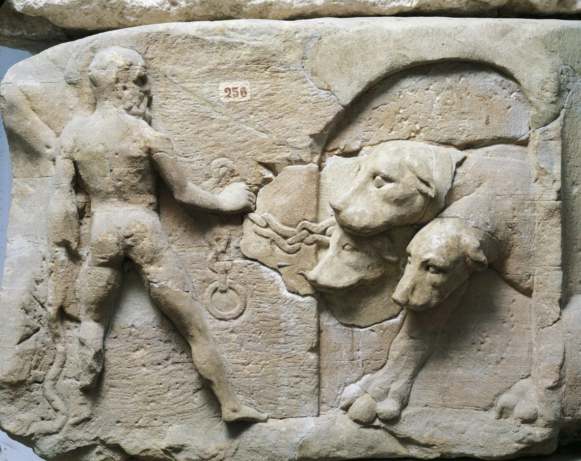Old stone relief from a mausoleum depicting Hercules chaining the three-headed dog Cerberus