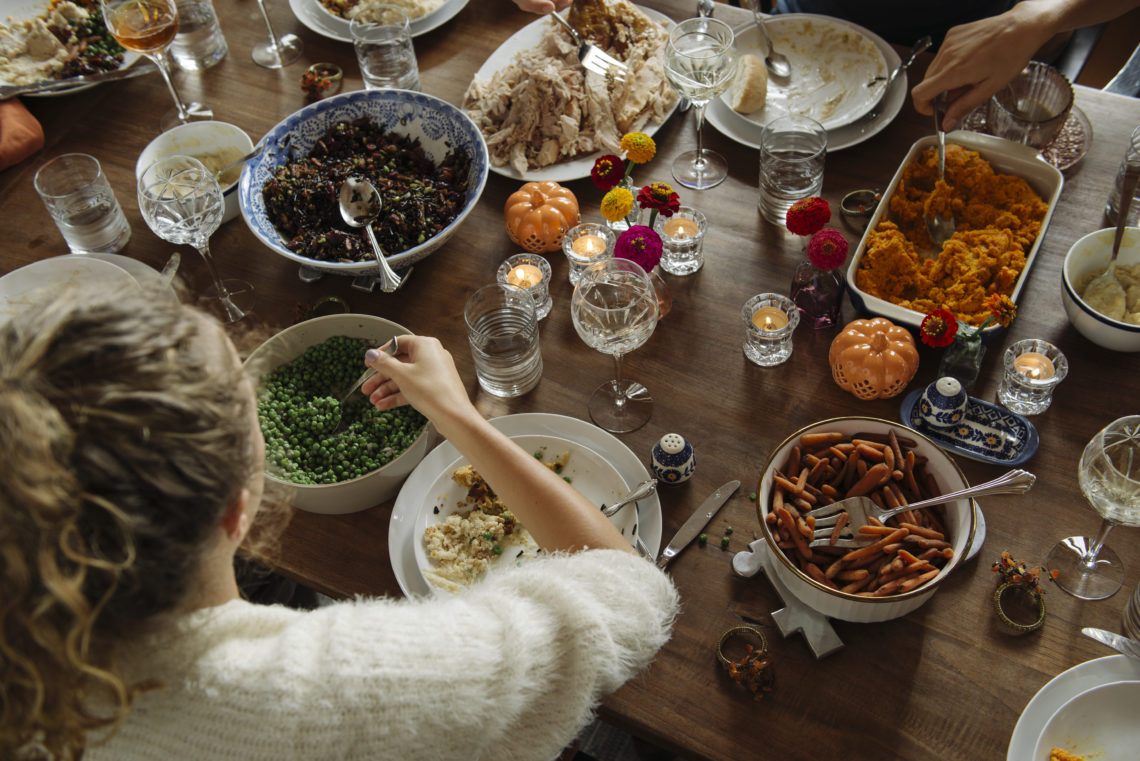 Teenage girl having food while sitting at dining table during Thanksgiving