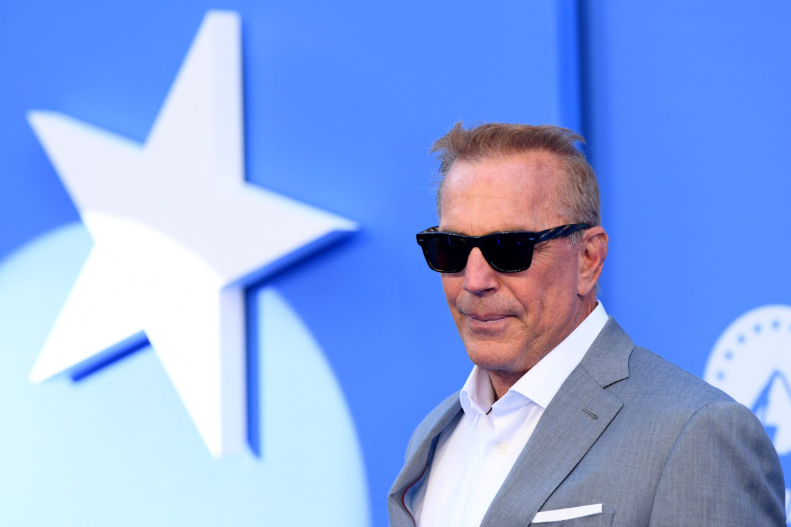 Kevin Costner poses for a photograph wearing dark sunglasses and a smart grey suit jacket at the Paramount+ UK launch in London