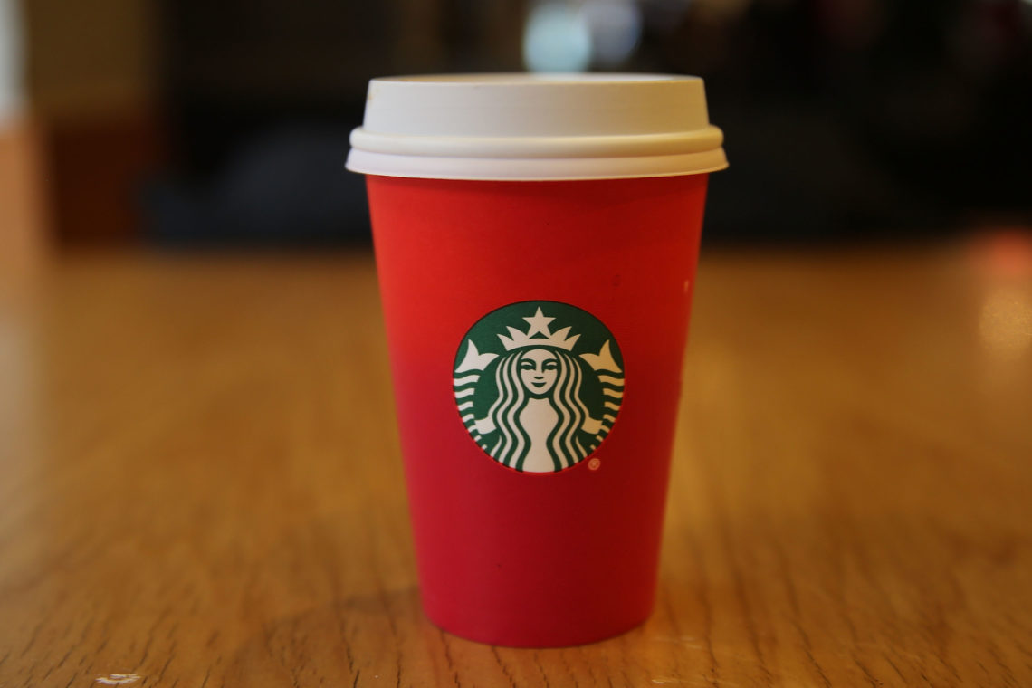 A plain Starbucks red cup sitting on a wooden table