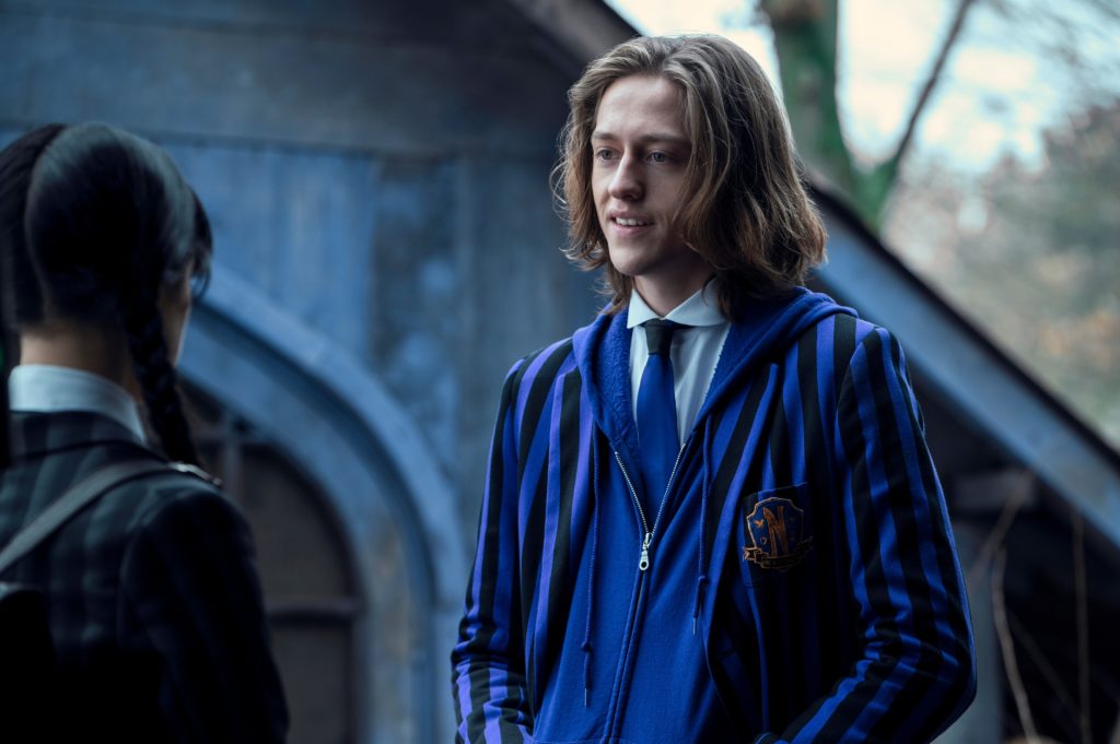 Xavier in his Nevermore Academy uniform looks at Wednesday on the school grounds