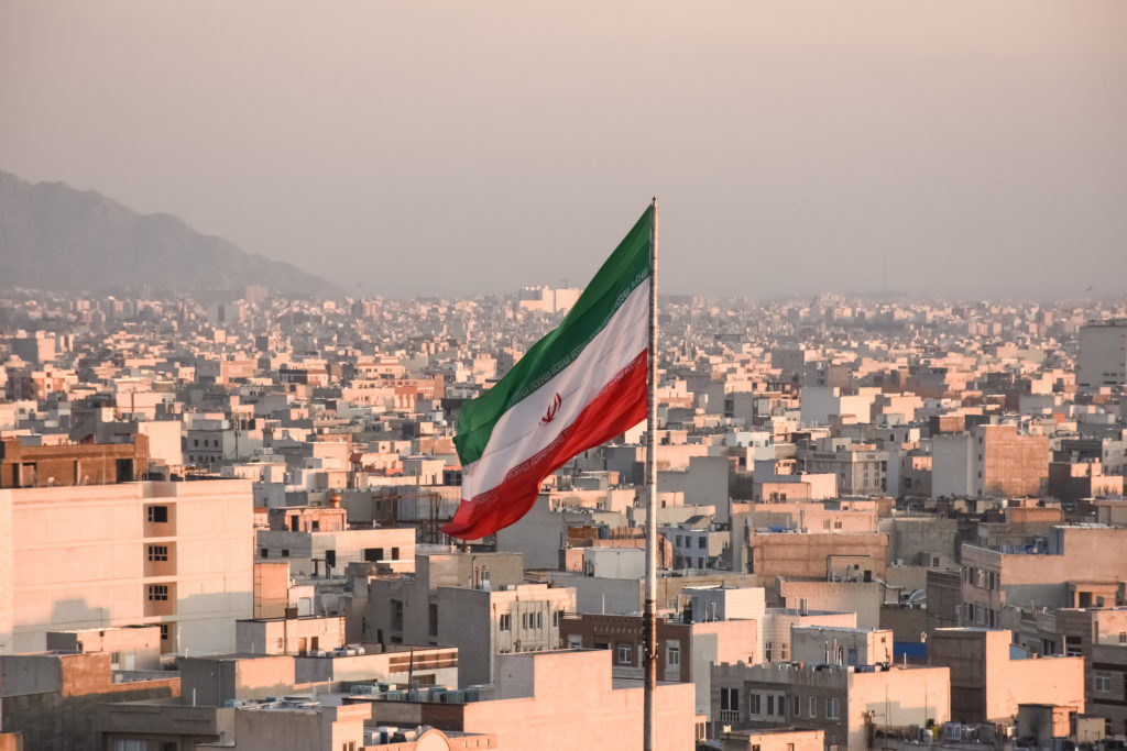 Iranian flag waving with city skyline on background in Tehran, Iran