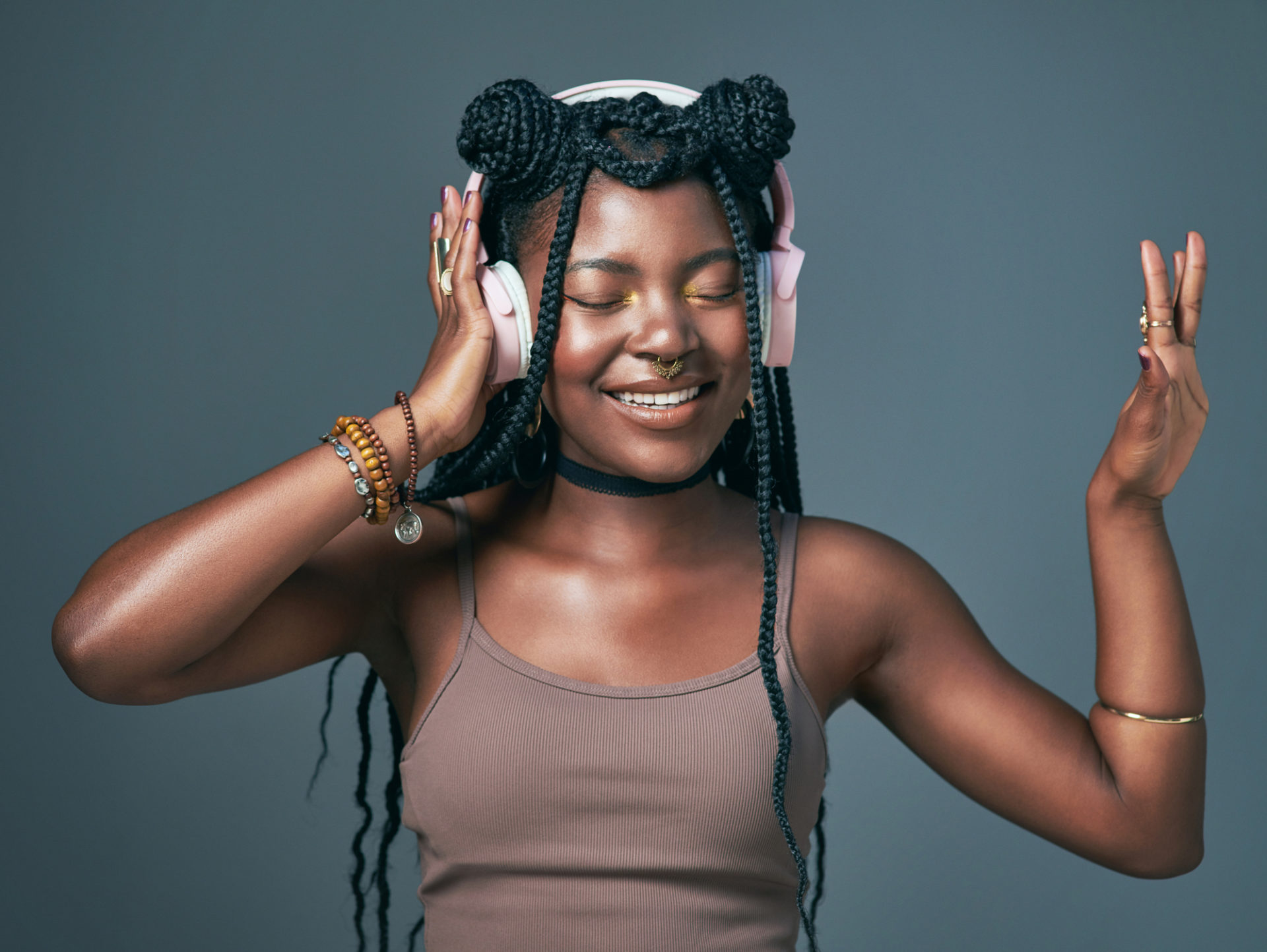 Studio shot of a trendy young woman using headphones against a grey background
