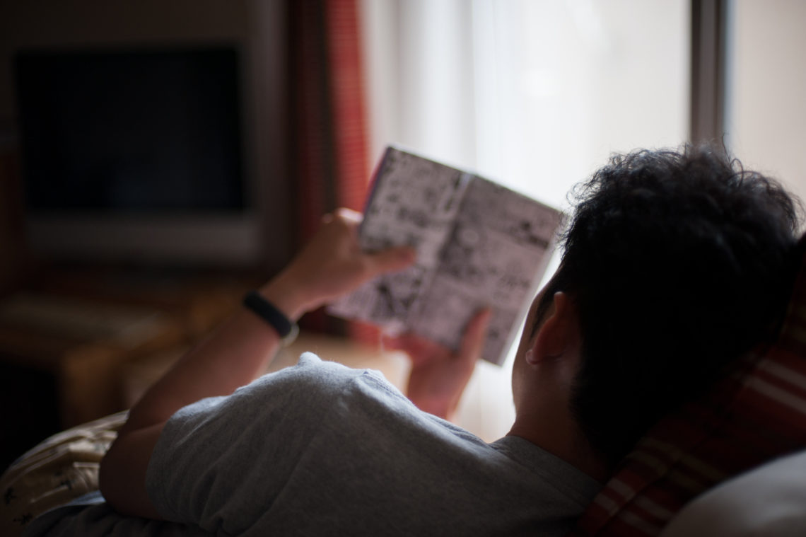 Man reading manga comic at home