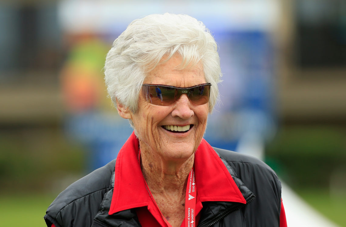 Kathy Whitworth smiles, wearing sunglasses and a red shirt with an oversized collar