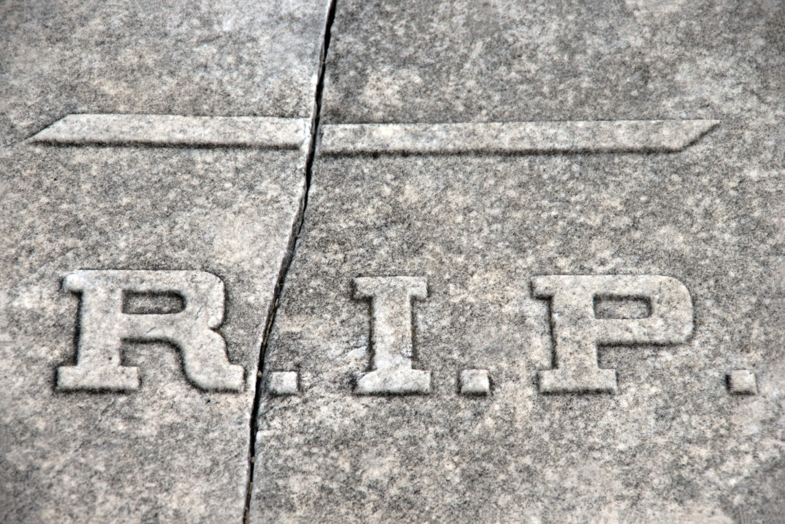 R.I.P. (Rest In Peace) abbreviation on a cracked granite tomb
