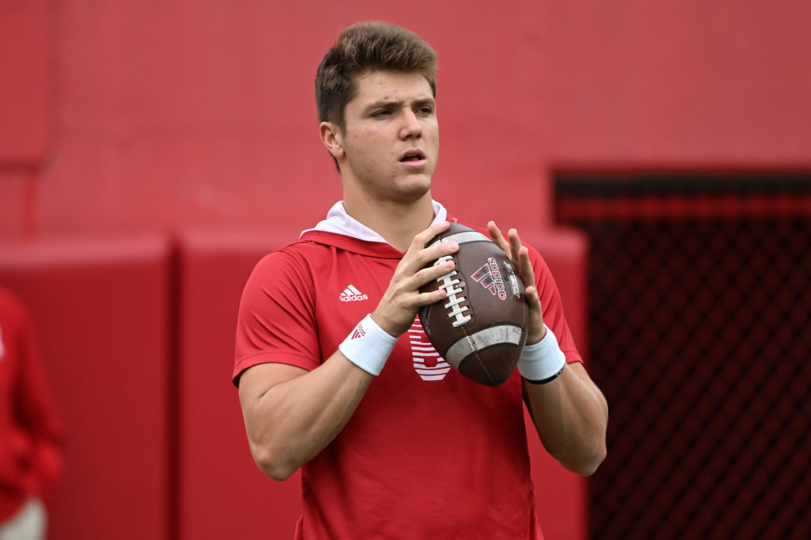 Nebraska Cornhuskers quarterback Chubba Purdy holding a football, with a red wall in the background