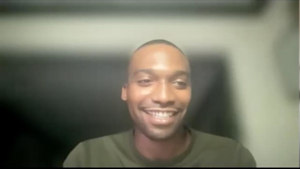 Quintin Bostic in a green sweater, taking part in an online interview