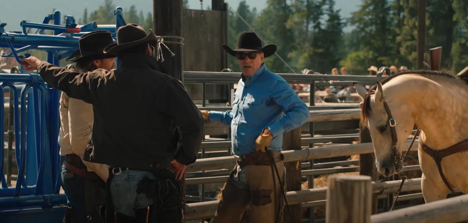 Los vaqueros se paran contra una valla sosteniendo un caballo en el rancho de Yellowstone