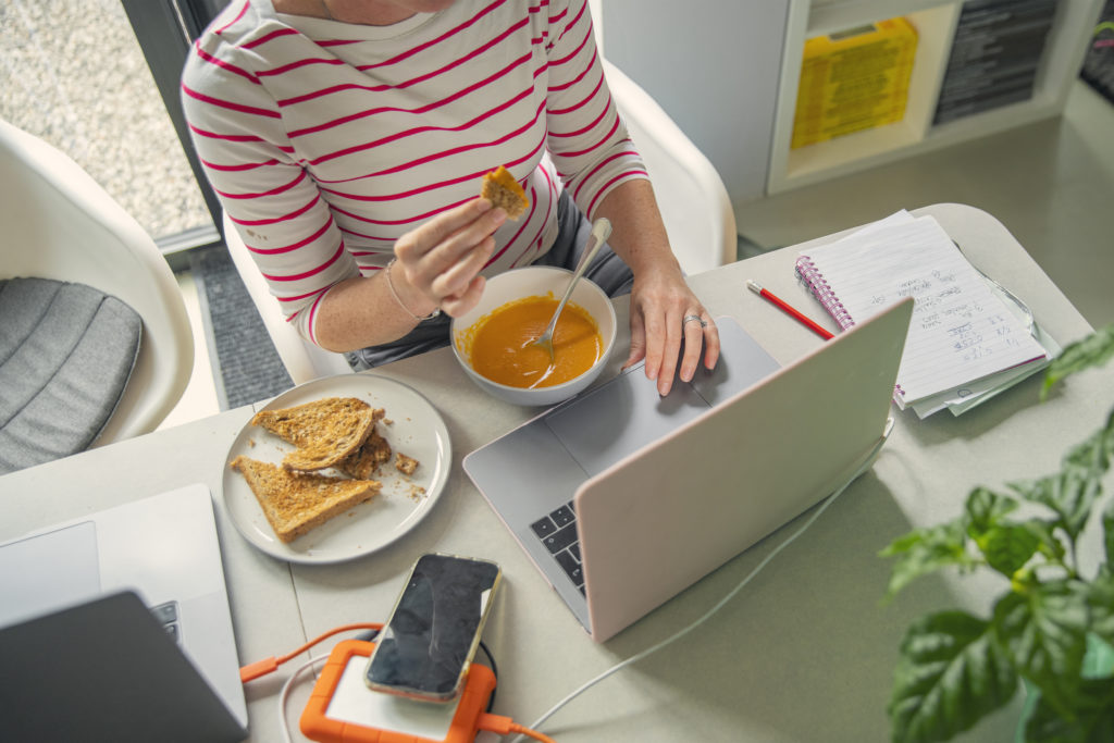 Mature woman eating her lunch whilst working from home